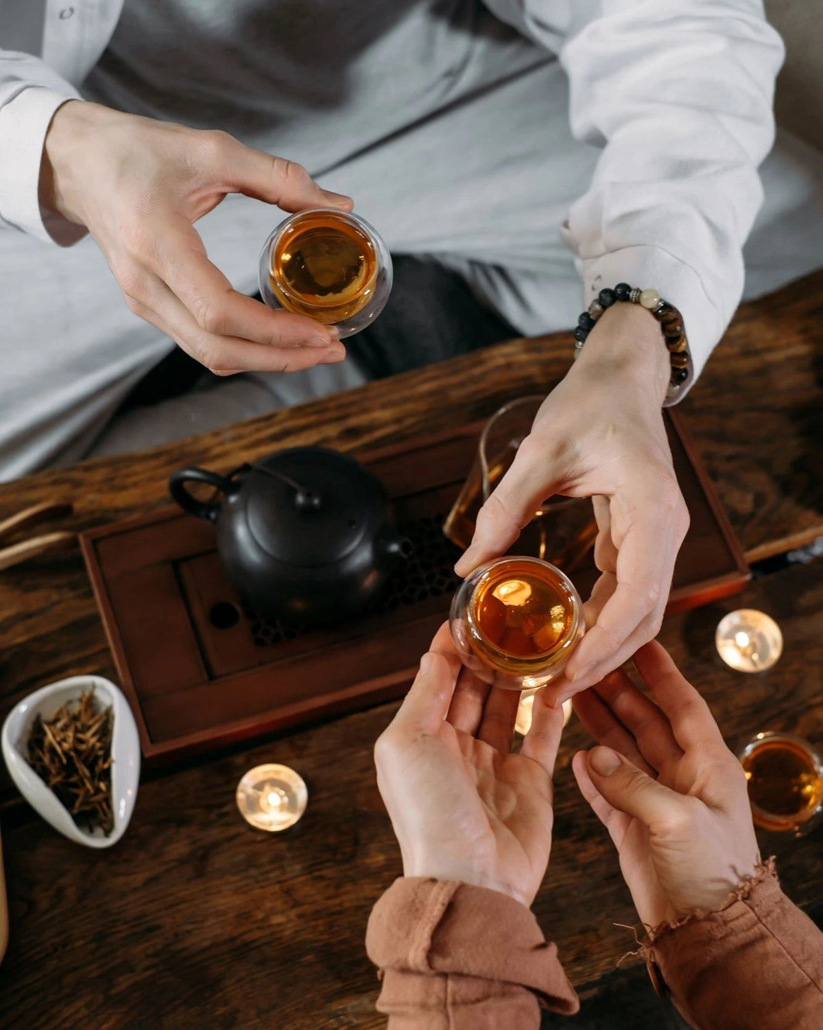 a close-up photo of a hand of a businessman handing a tea cup with organic black tea to a client